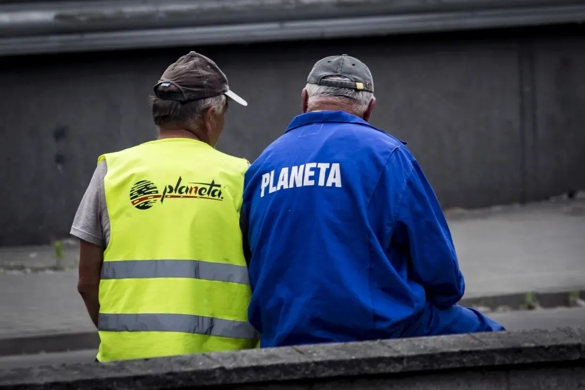 Two sanitation workers seen from behind in blue and yellow uniforms